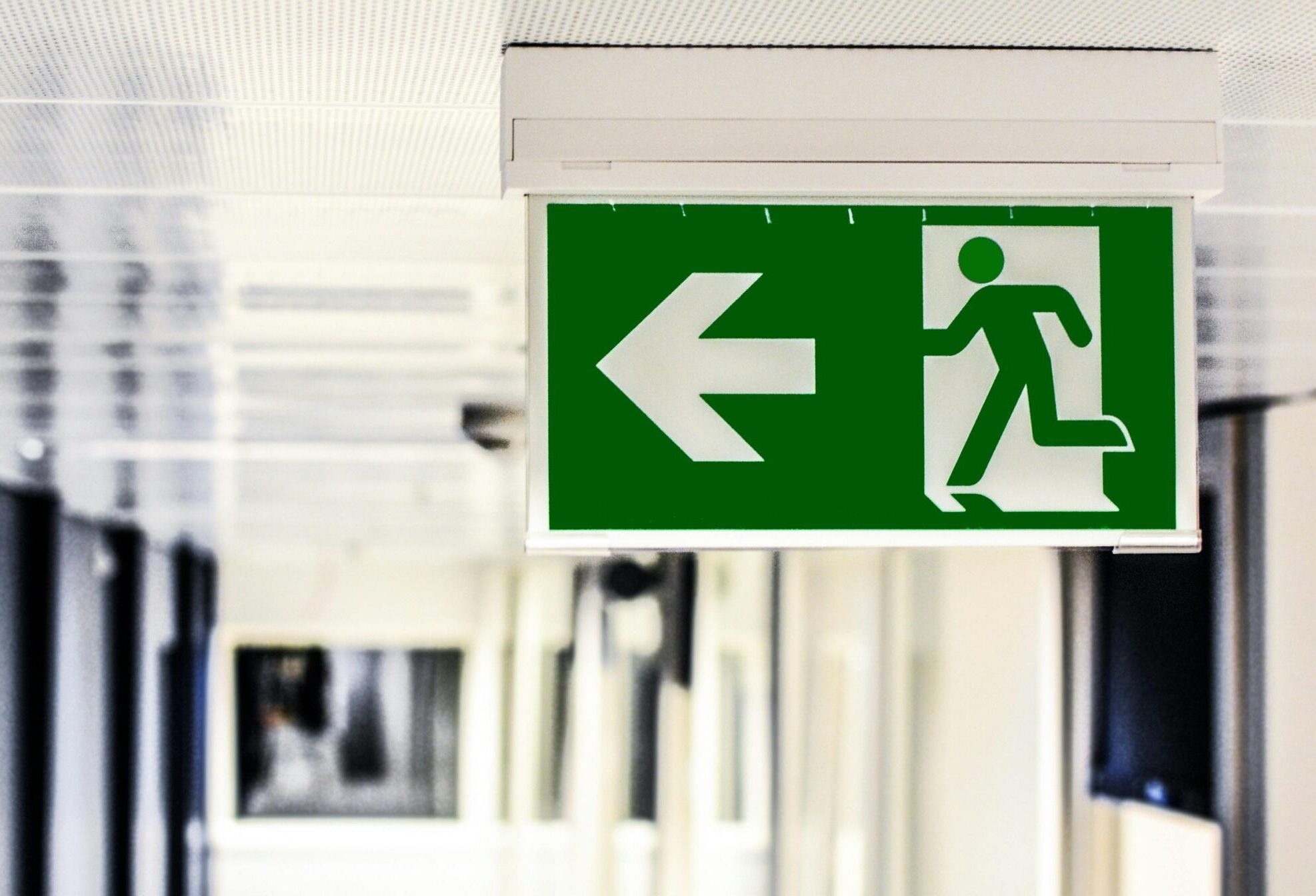 Green emergency exit sign with directional arrow in a hallway.