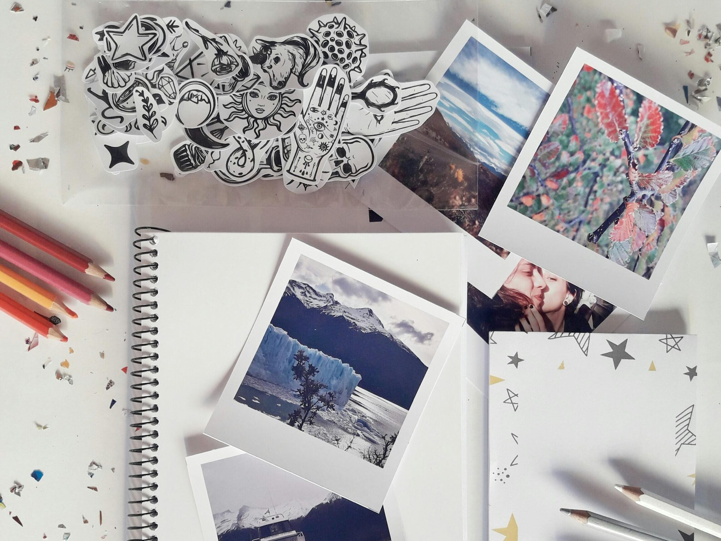 Flat lay of a creative desk setup with photos, notebook, and stationery for artistic inspiration.